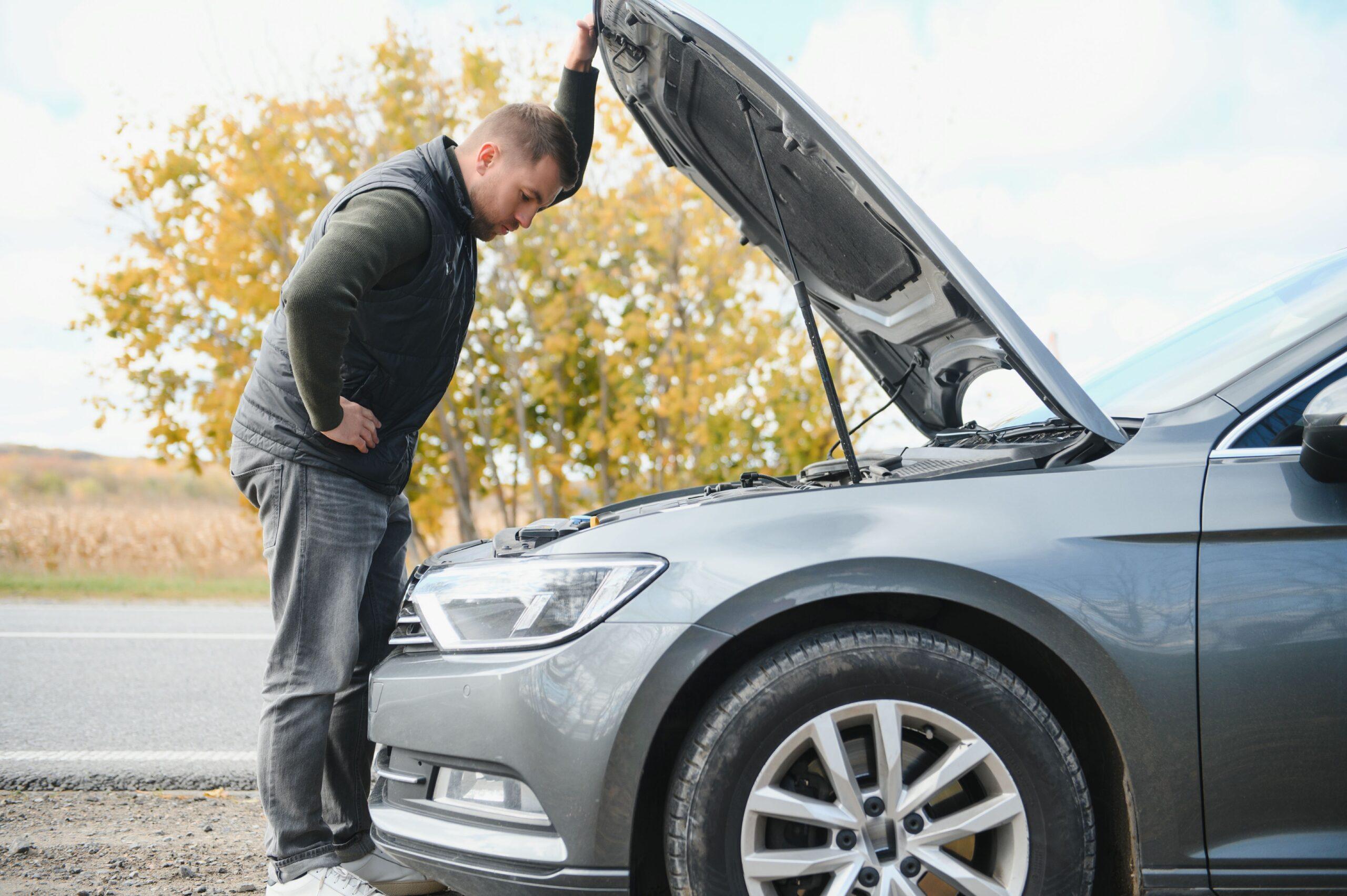 Mann guckt unter die Motohaube seines Autos