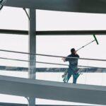 Reinigungskraft reinigt große Glasflächen in einem Gebäude