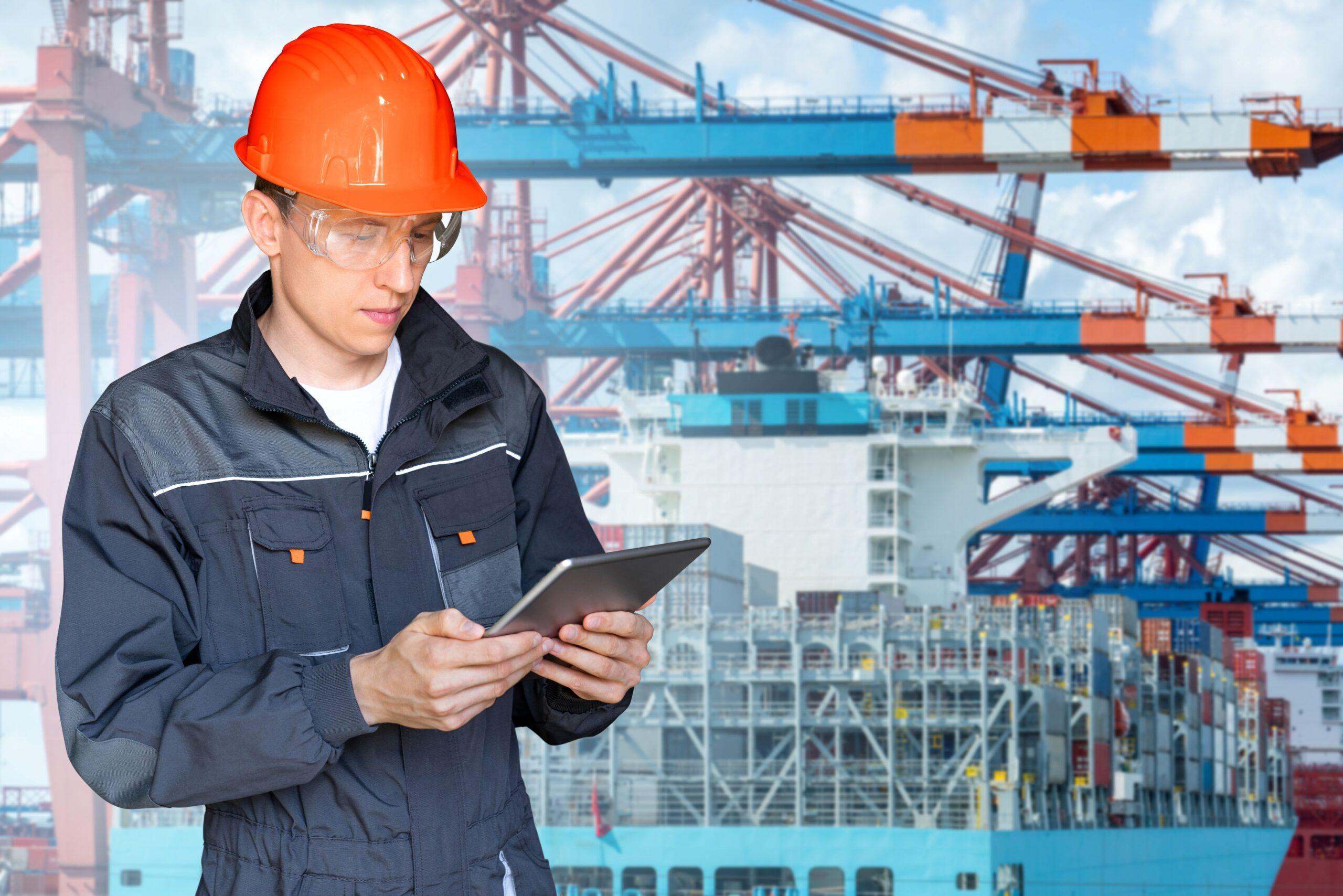 Hafenarbeiter mit Tablet vor Containerbrücke – Verbindung von Erfahrung und digitaler Steuerung