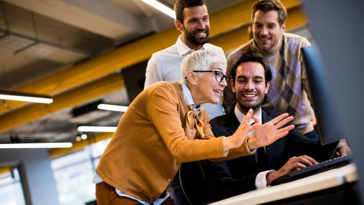 Motiviertes Team arbeitet gemeinsam am Schreibtisch | Lohnabrechnung Outsourcing